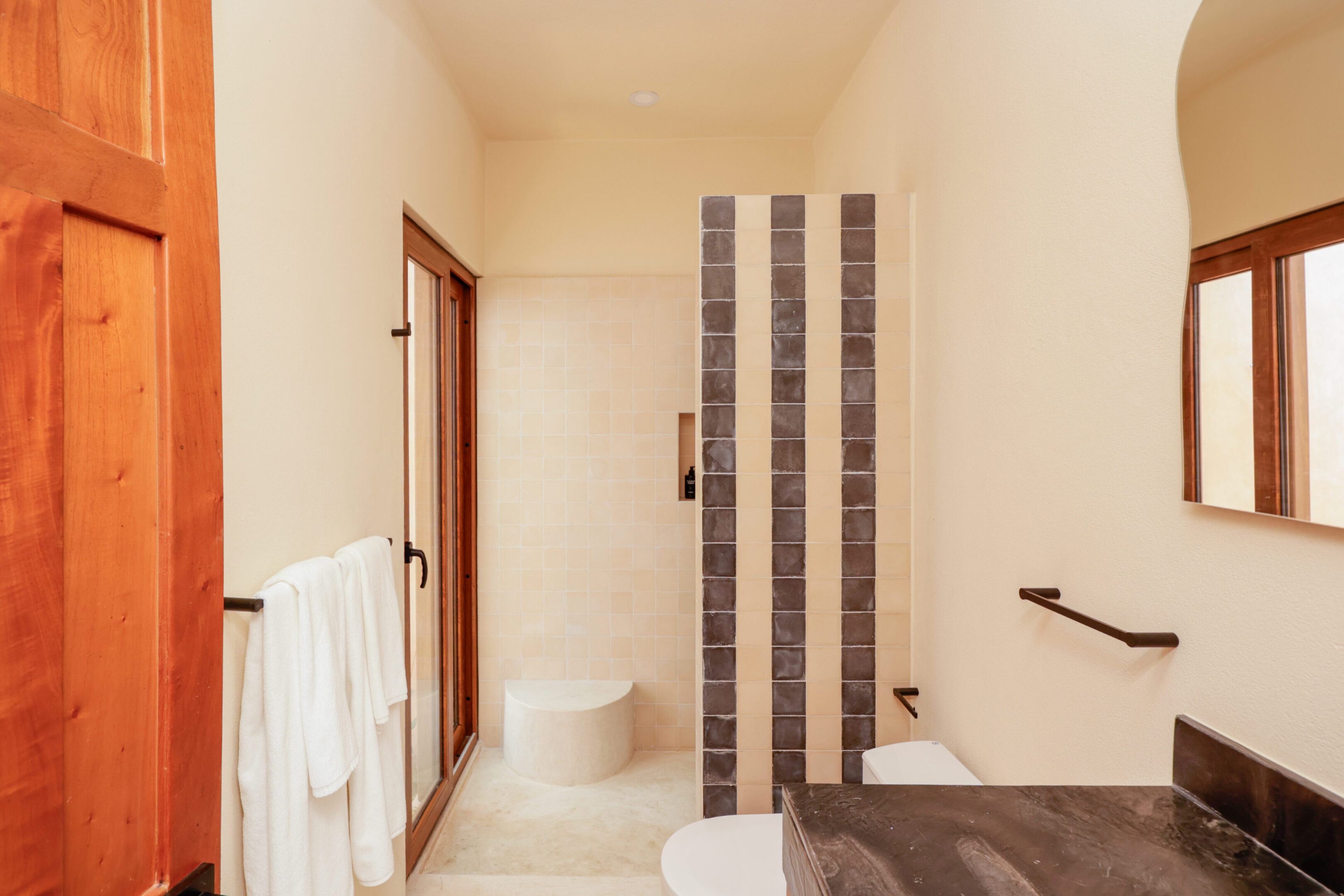 Minimalist bathroom with beige tiles and vertical dark stripes.