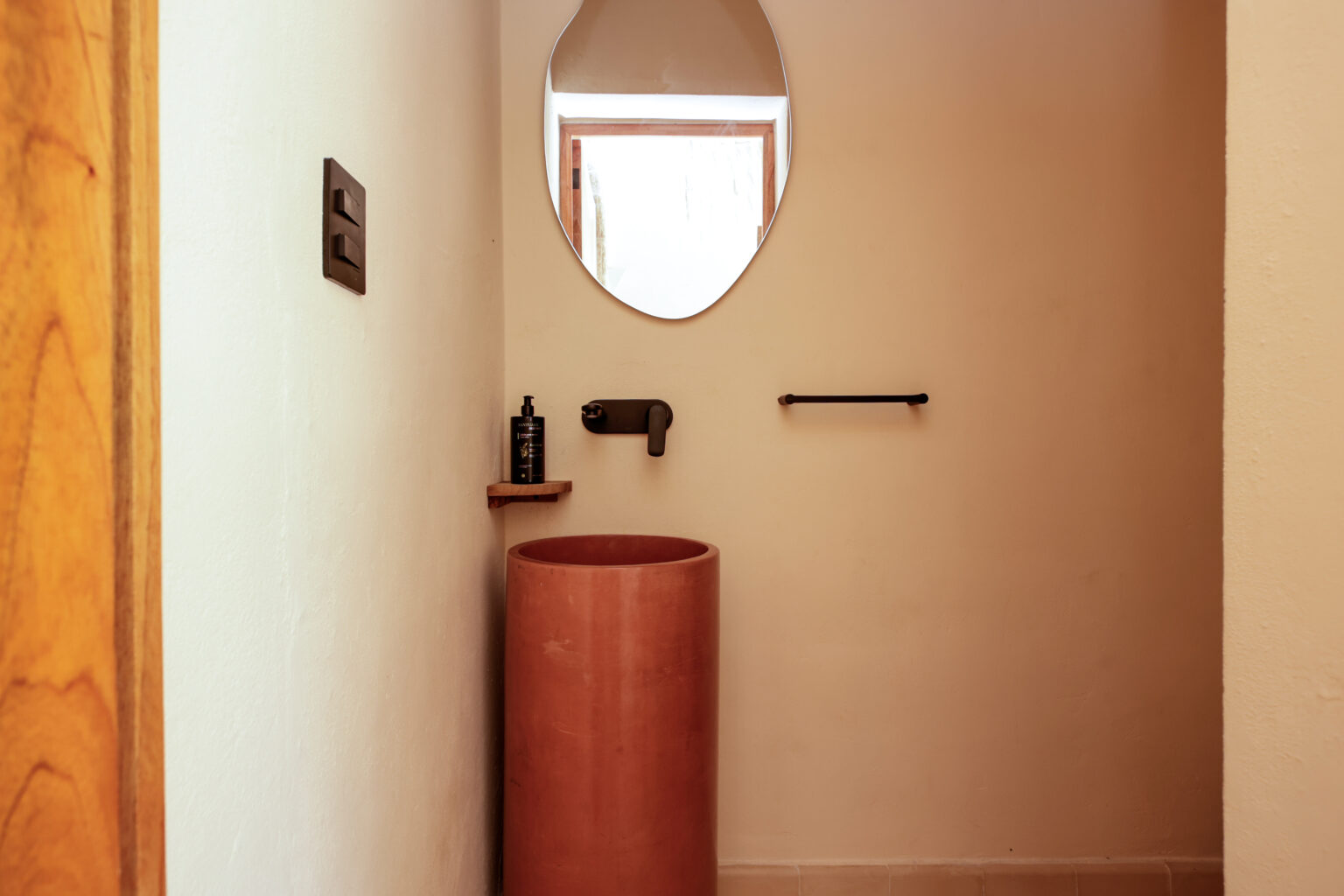 Minimalist bathroom with a round terracotta sink and soft natural light.