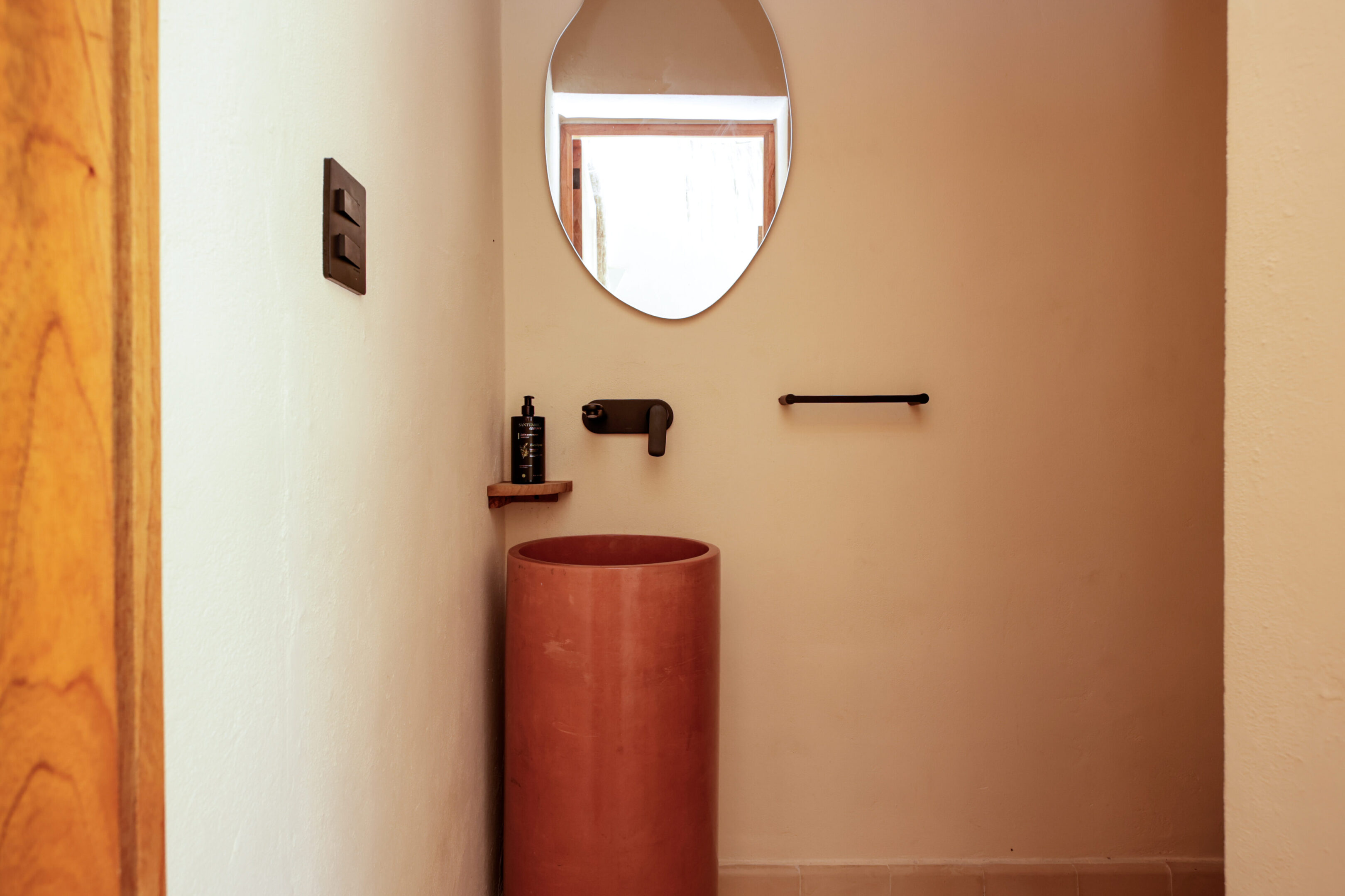 Minimalist bathroom with a round terracotta sink and soft natural light.