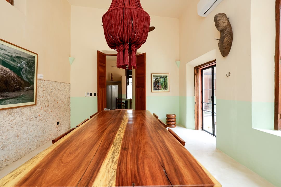 Elegant dining room with a large wooden table and red chandelier.