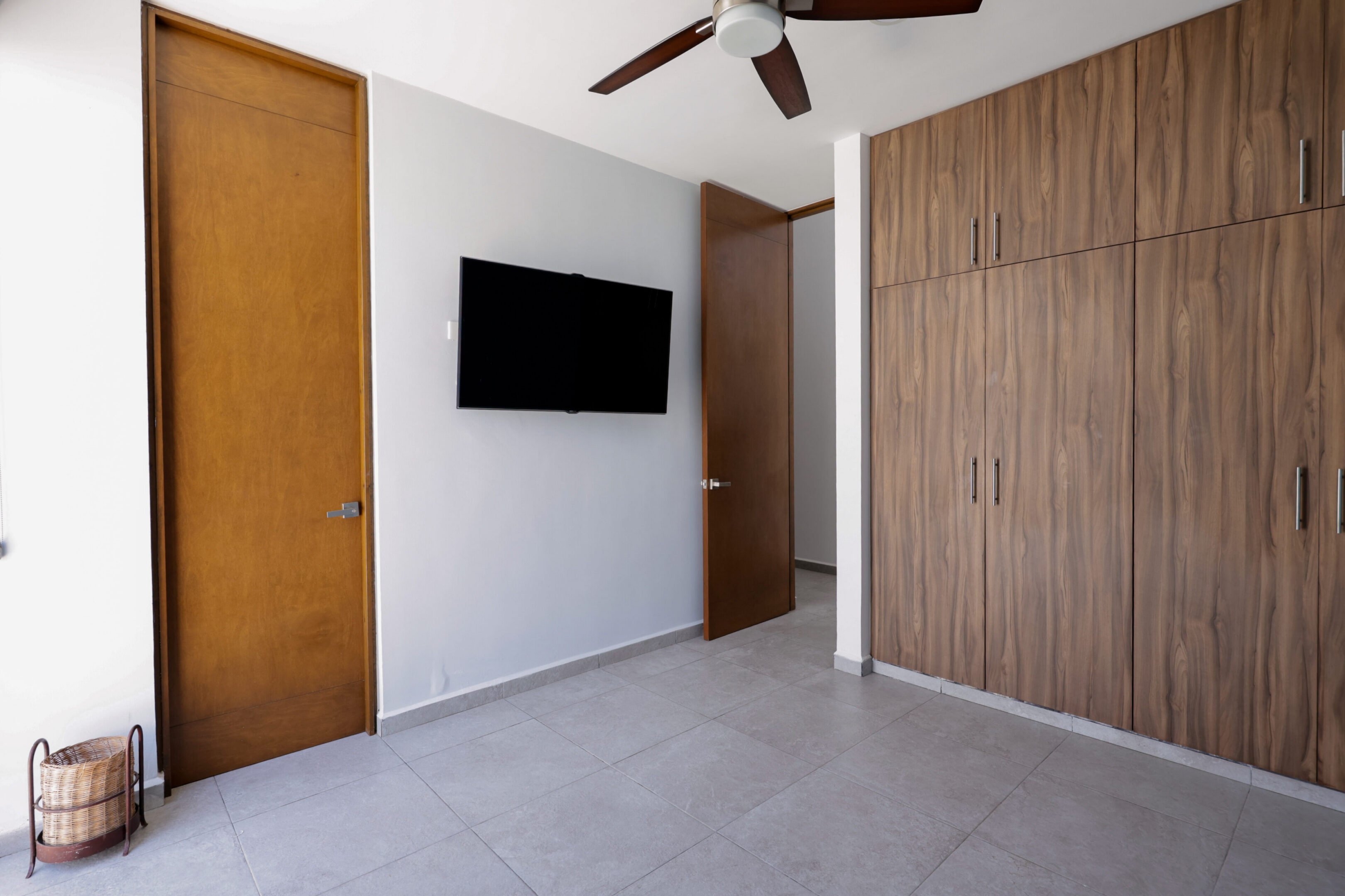 Modern bedroom with wood accents and a wall-mounted TV.