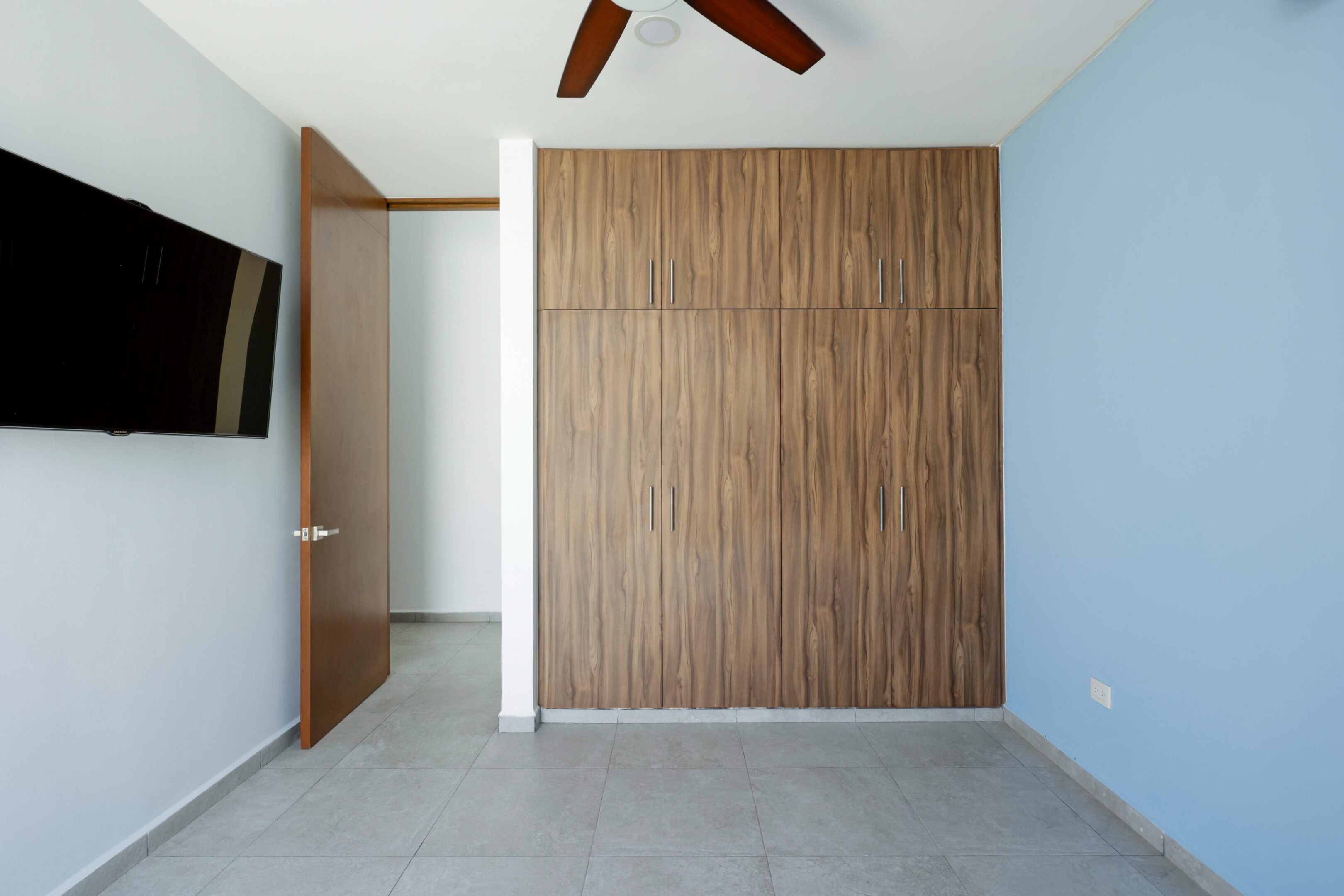Minimalist room with a wooden accent wall and ceiling fan.