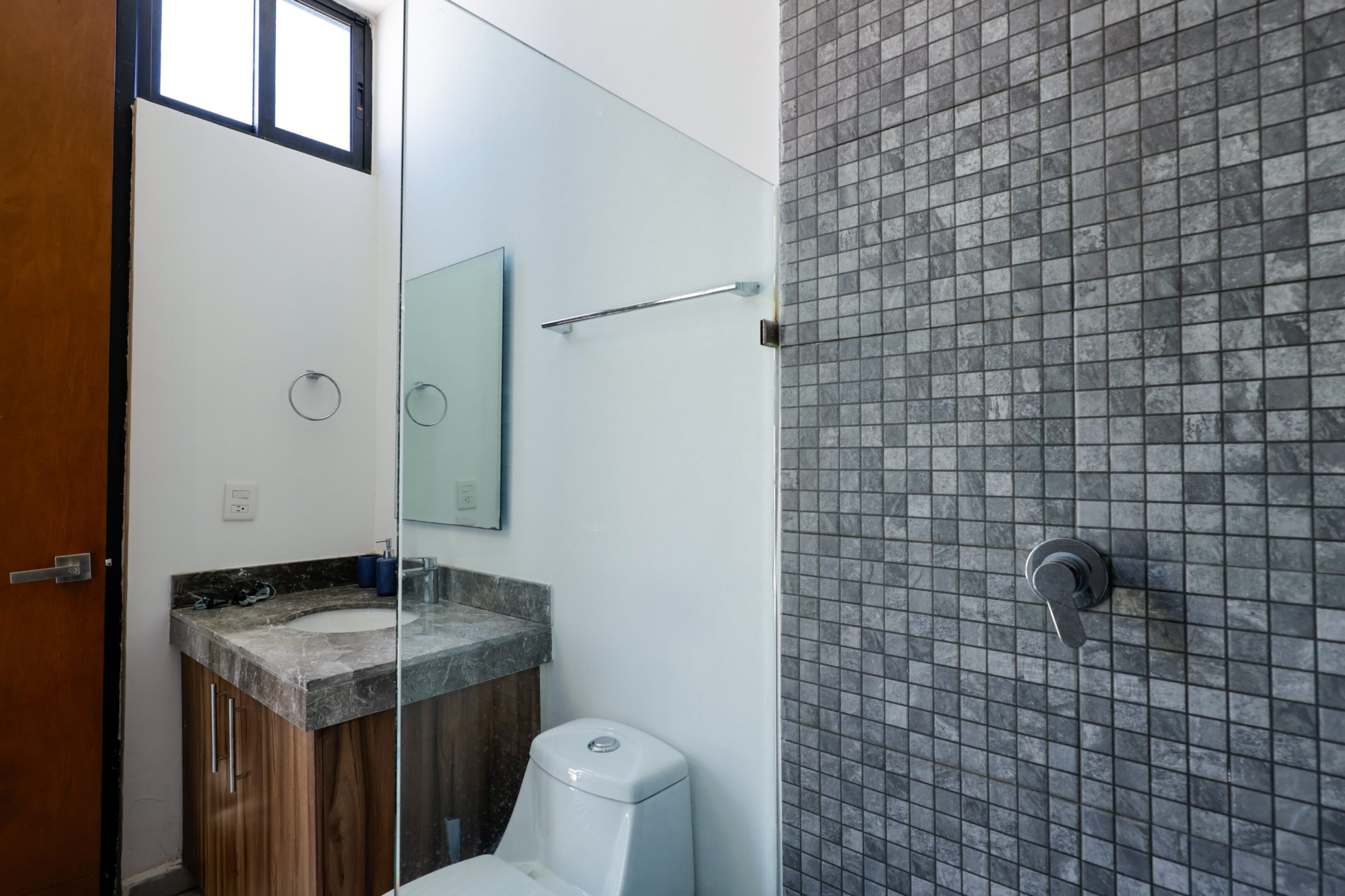 Modern bathroom with gray tiles and wooden vanity.