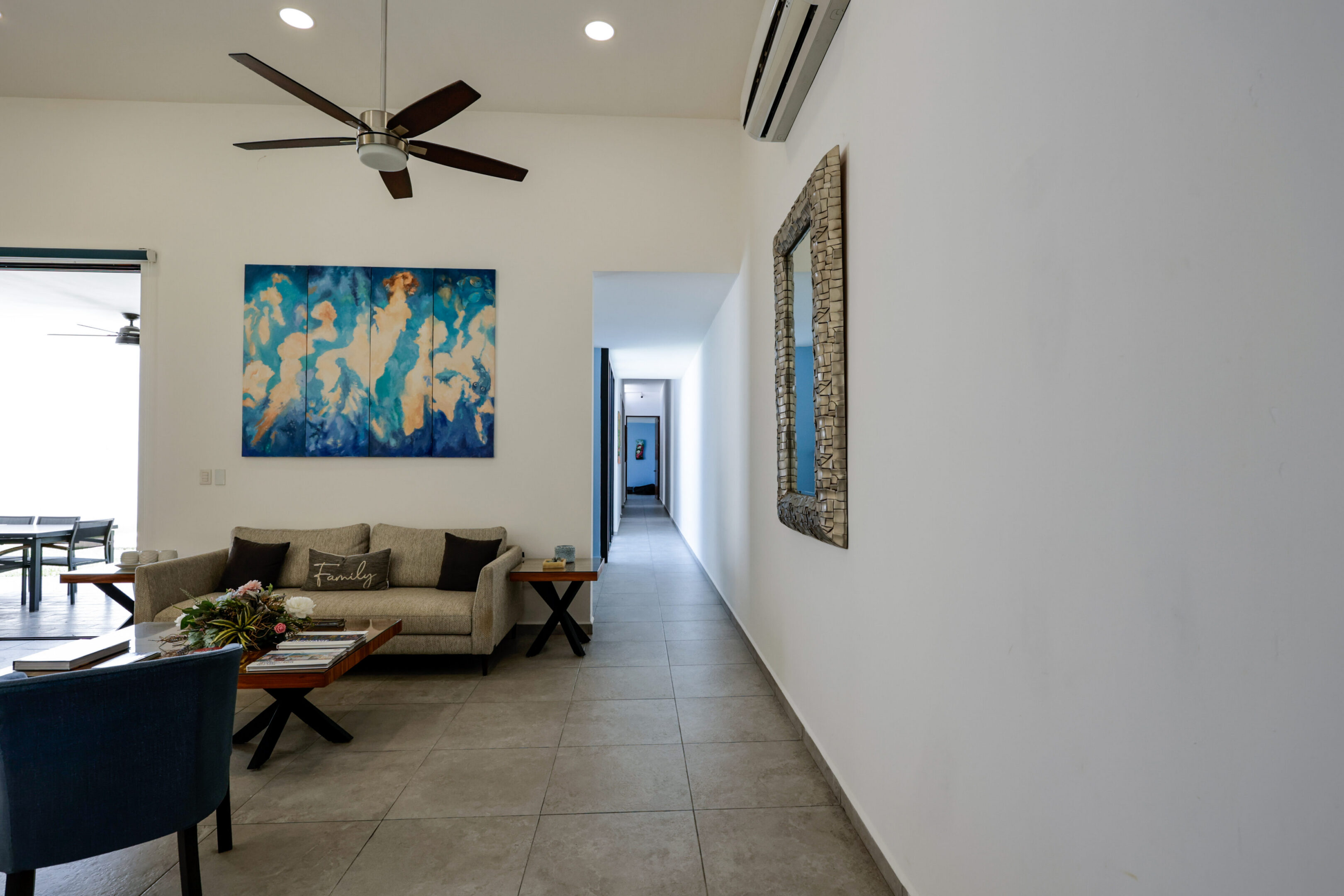 Modern living room with sofa, artwork, and ceiling fan.