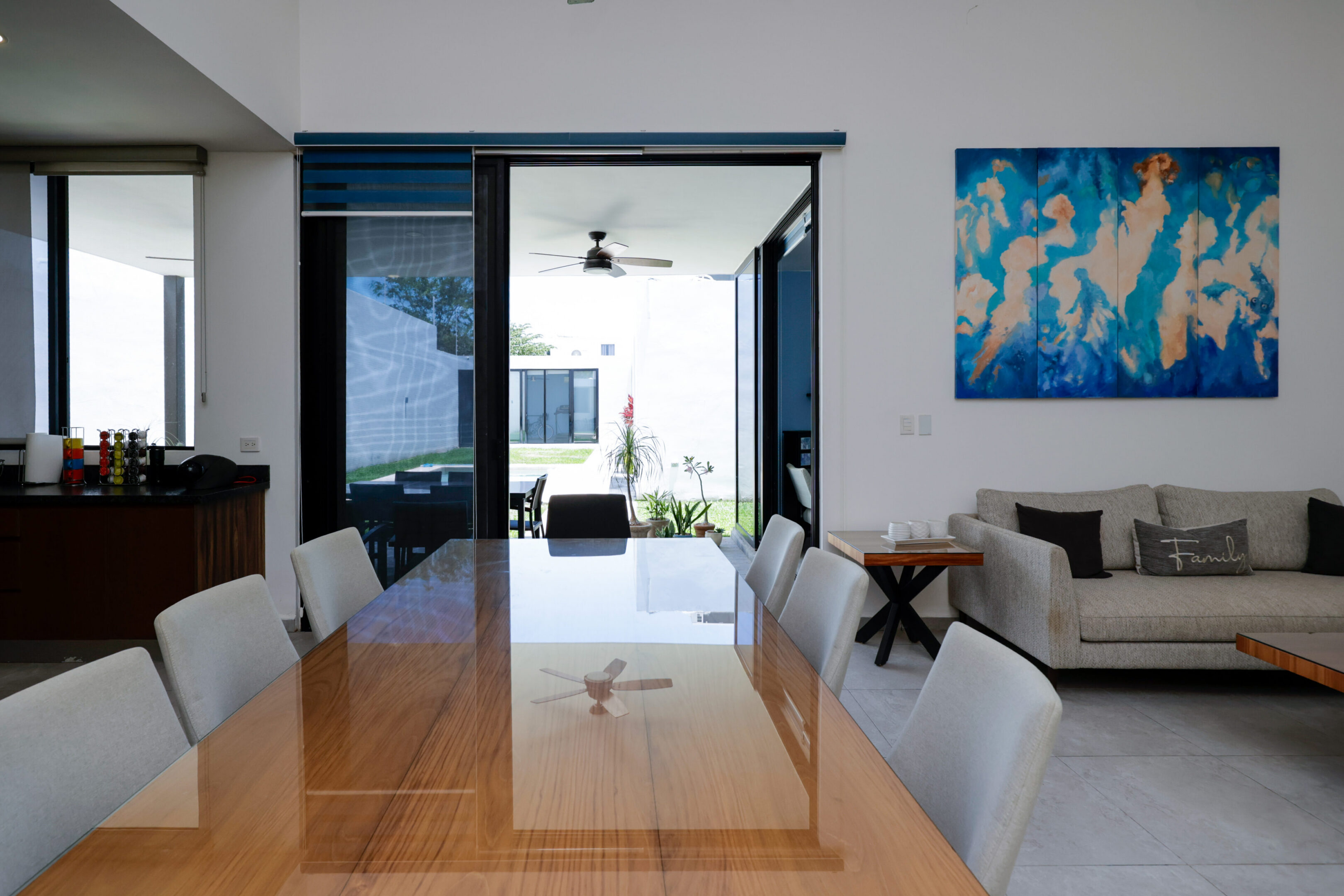 Modern dining room with wooden table and open view to balcony.
