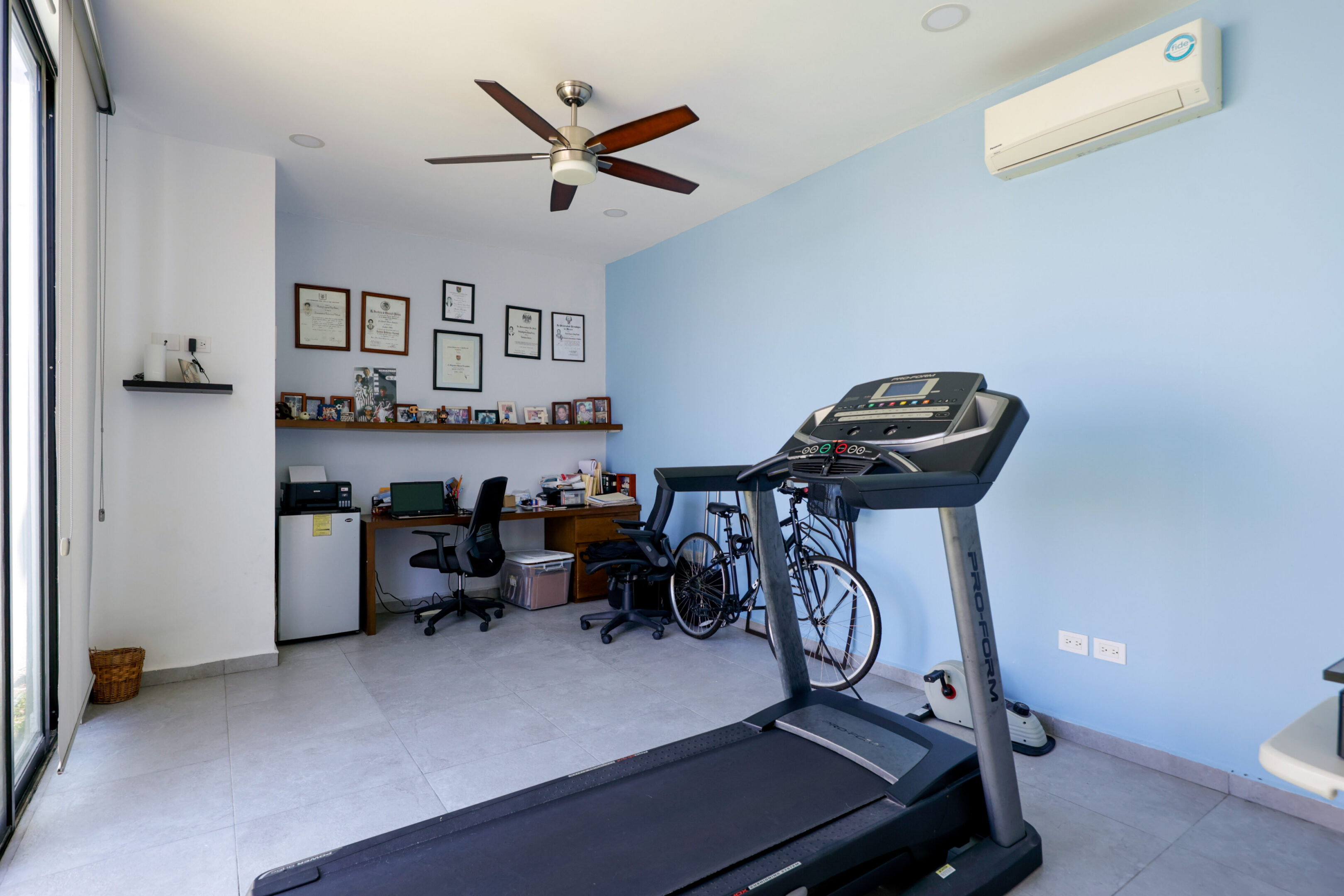 Home gym and office space with treadmill and desk setup.