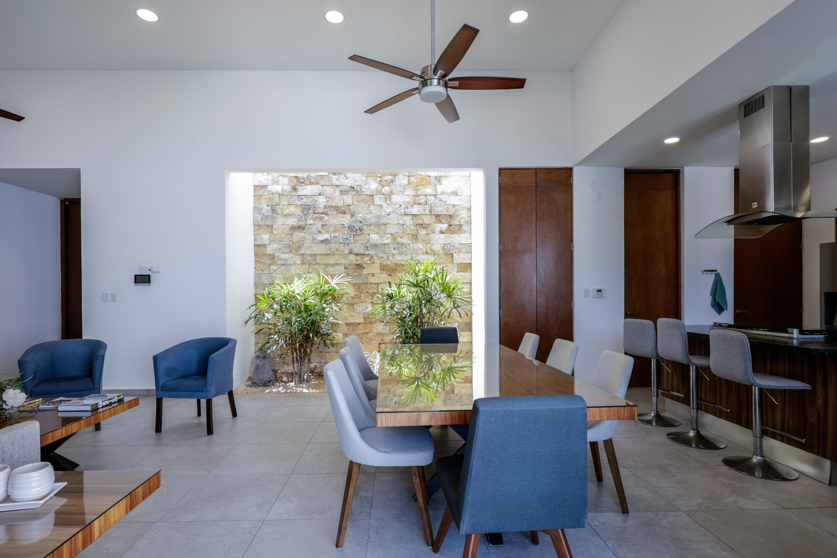 Modern dining area with blue chairs and a stone accent wall.