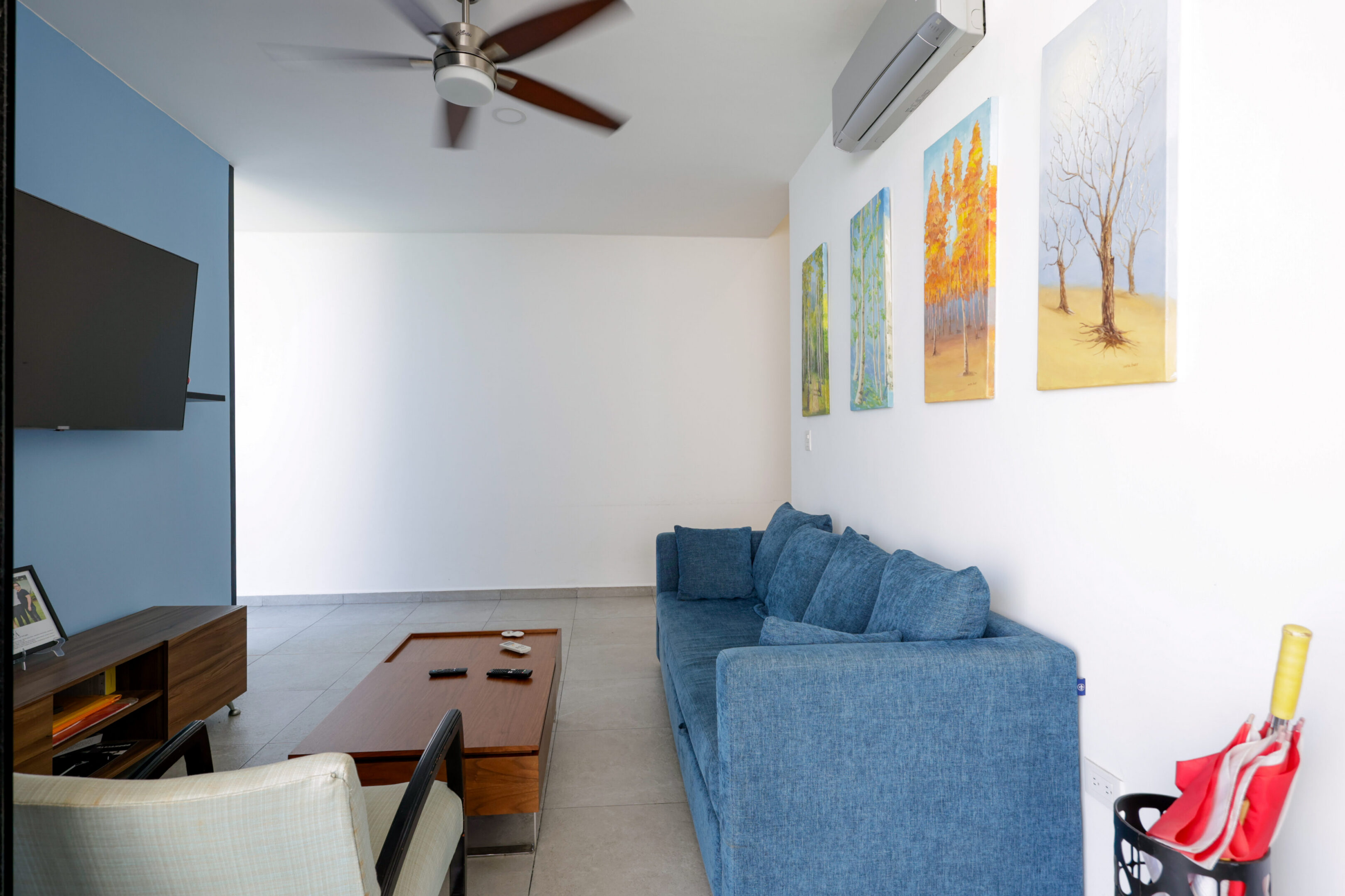 Modern living room with blue sofa and colorful wall art.