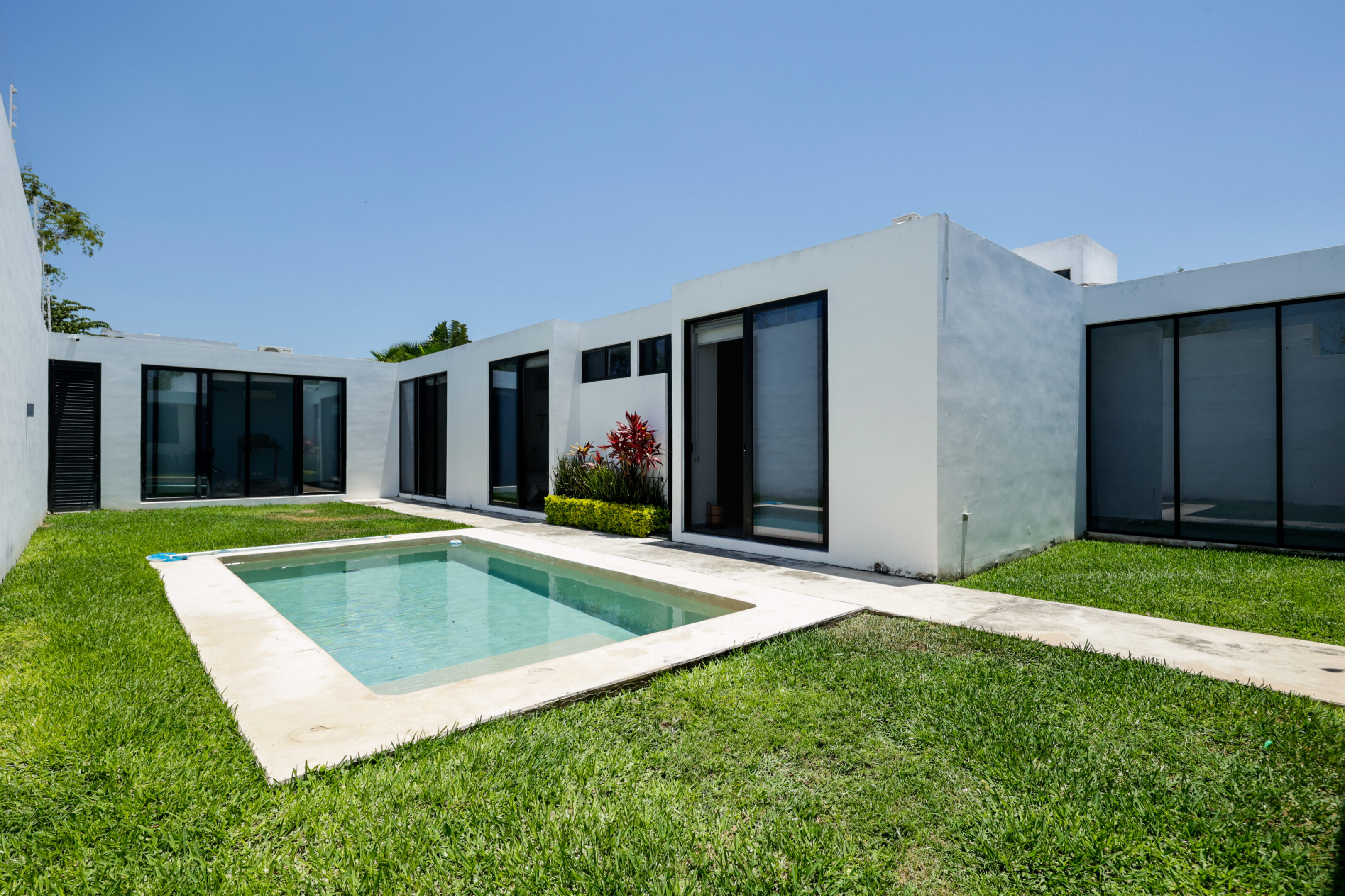 Modern house with a small pool and lush green lawn.
