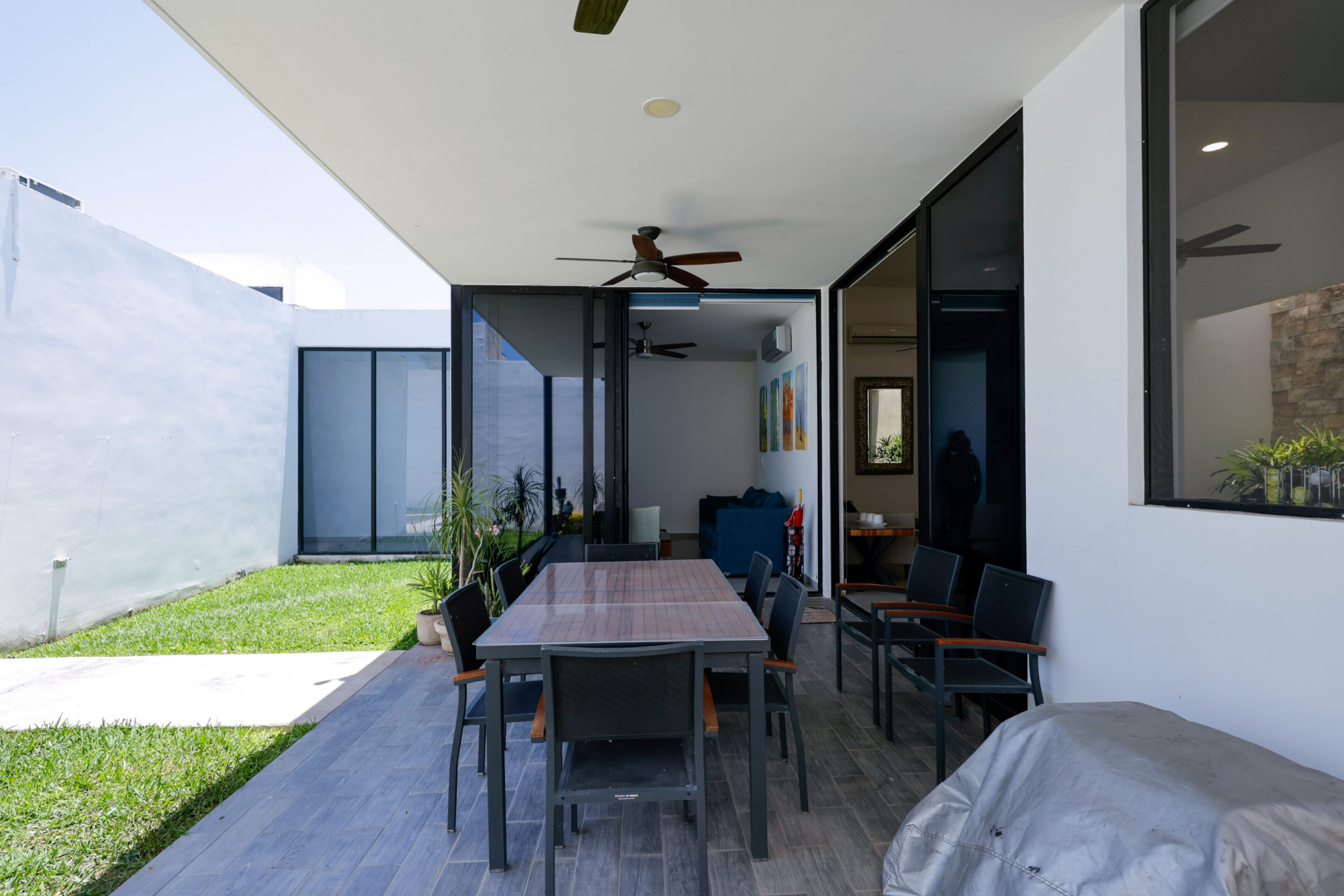 Modern outdoor patio with dining table and ceiling fan.