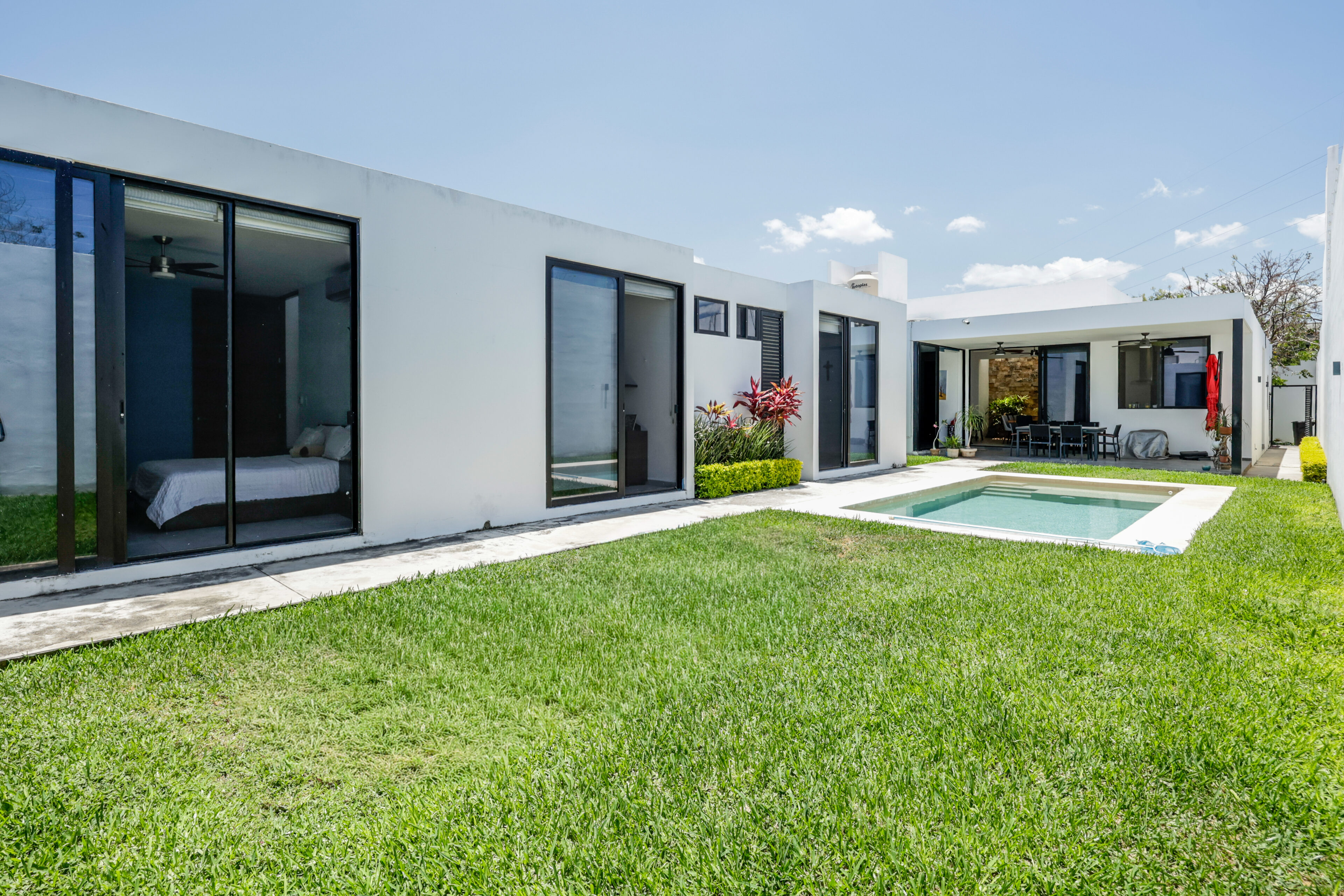 Modern white house with large windows and a swimming pool.