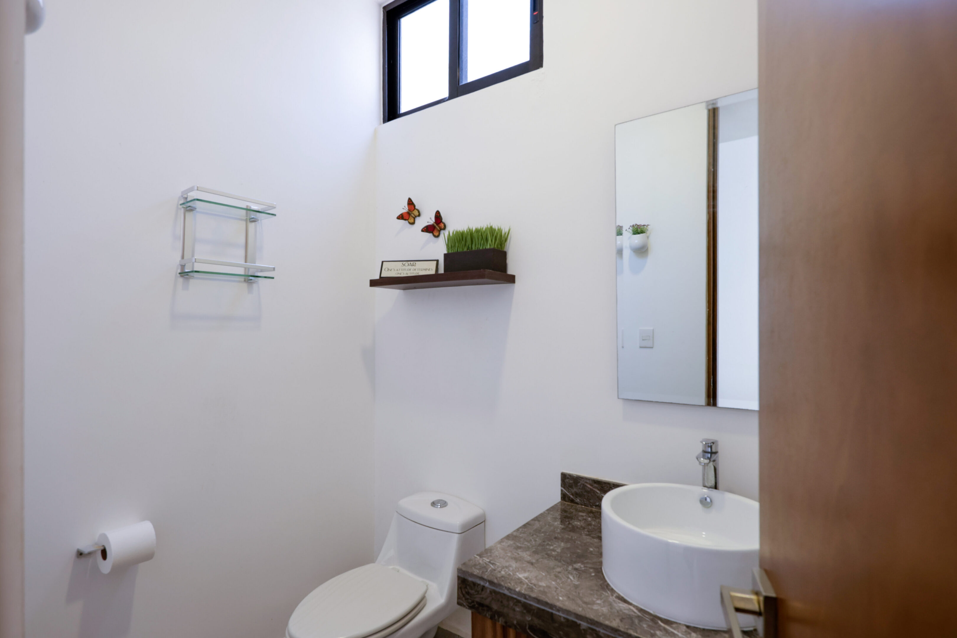 Minimalist bathroom with white walls, a small shelf, and a round sink.