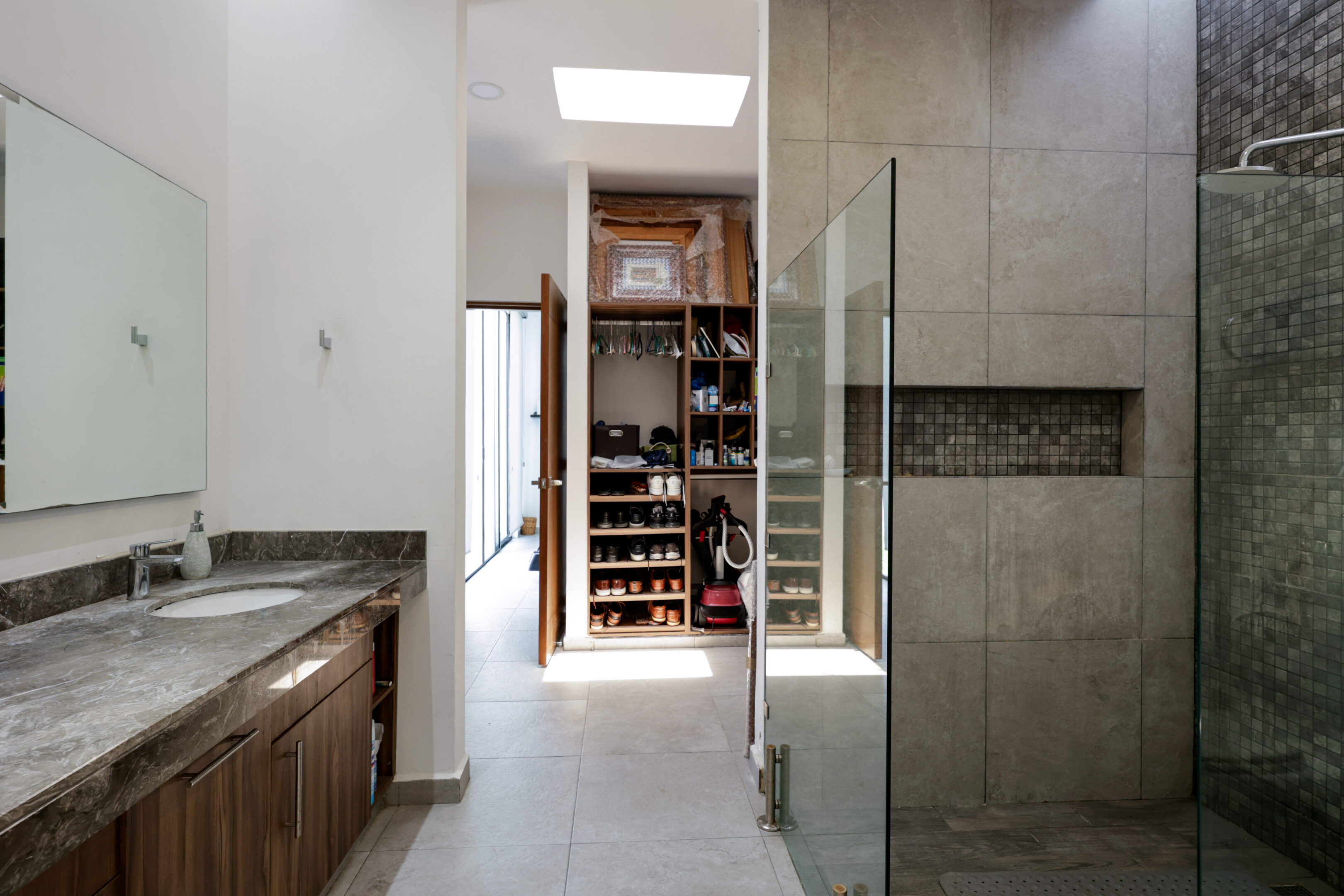 Modern bathroom with glass shower and walk-in closet.