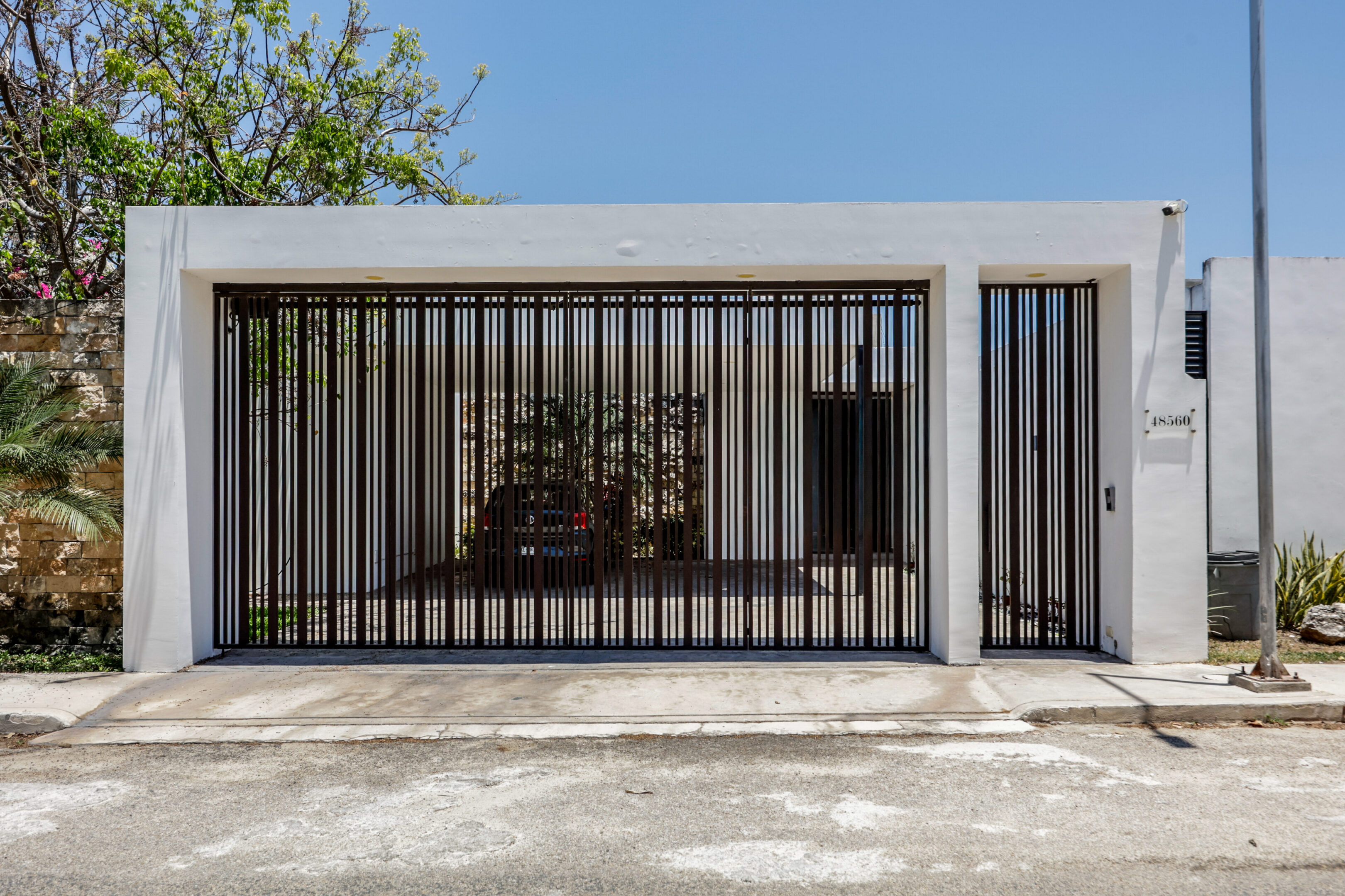 Modern house entrance with vertical metal bars and white walls.