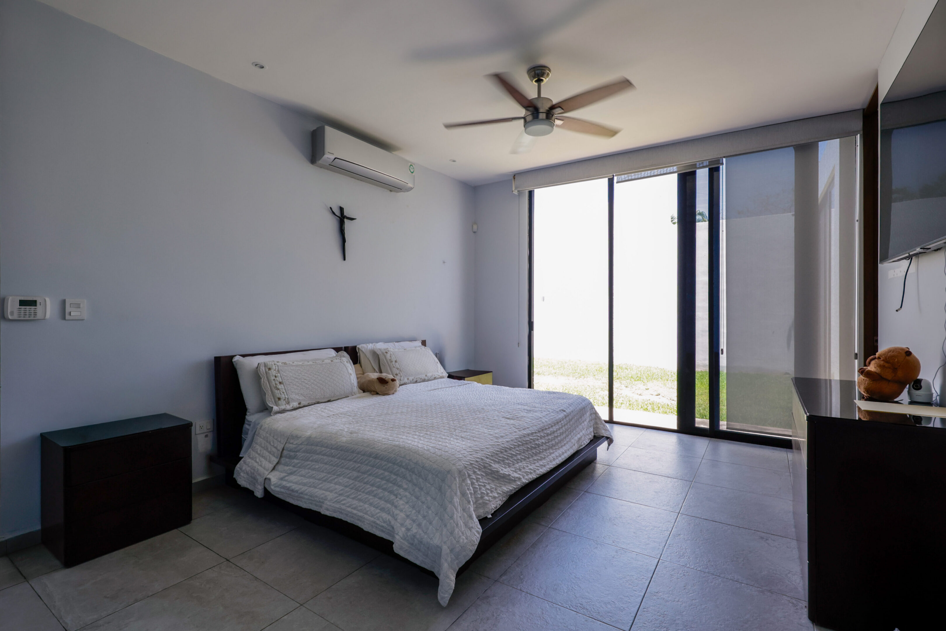Minimalist bedroom with a large window and ceiling fan.