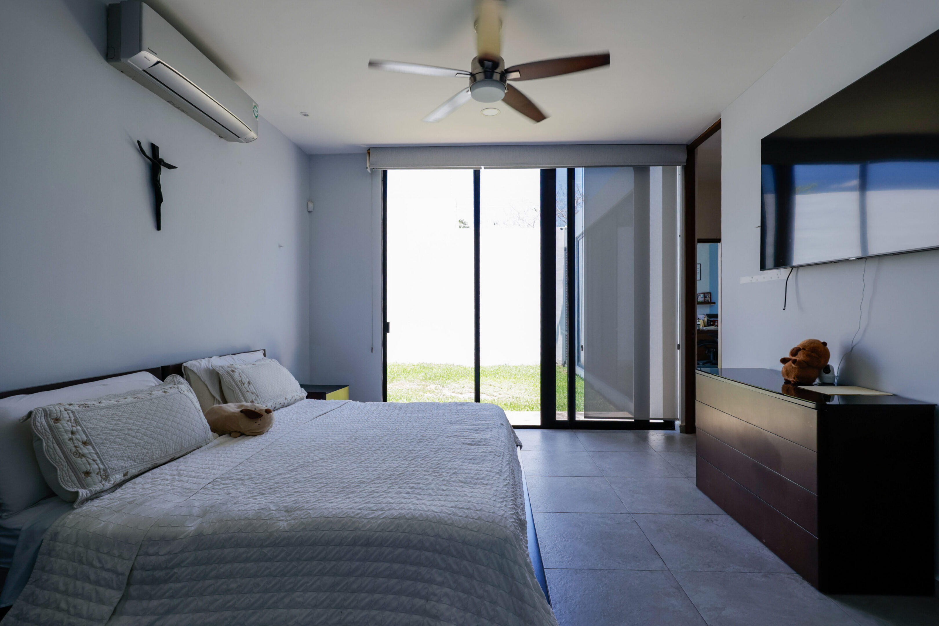 Bright bedroom with sliding glass doors and ceiling fan.