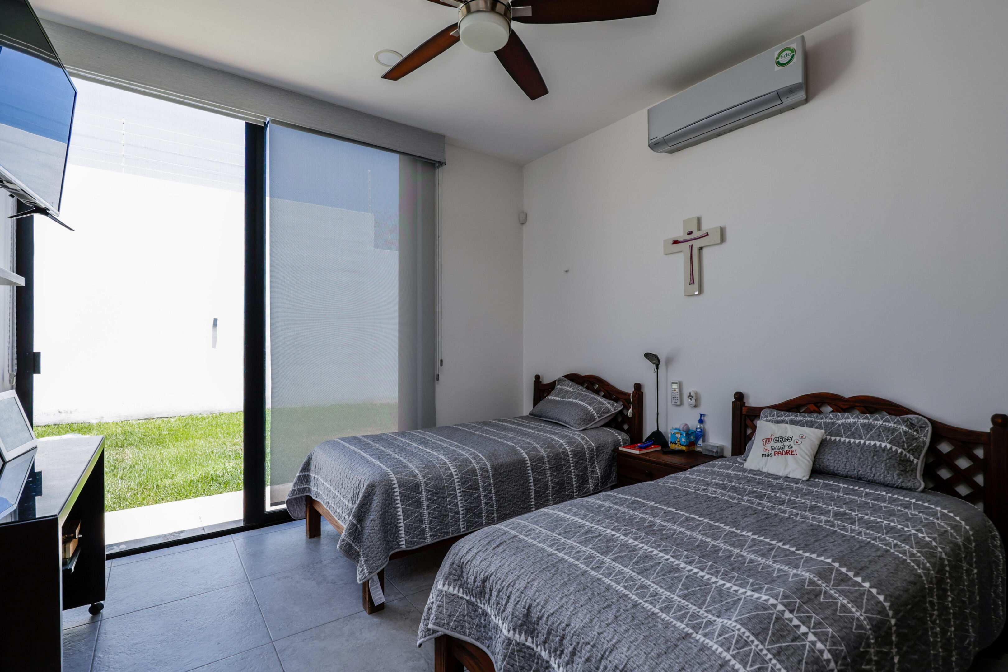 Minimalist bedroom with two twin beds and large window overlooking a garden.