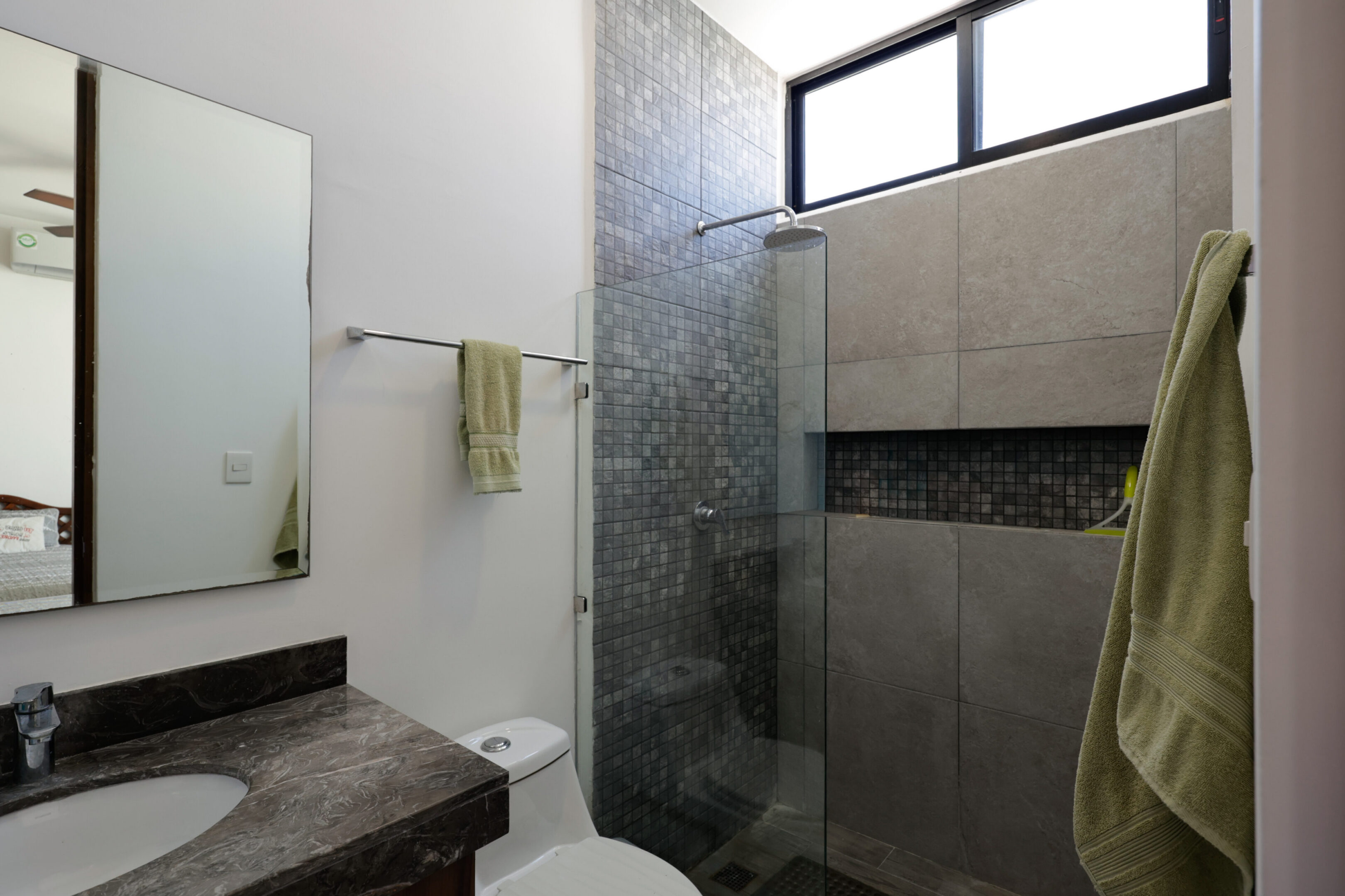 Modern bathroom with glass shower enclosure and stone accents.