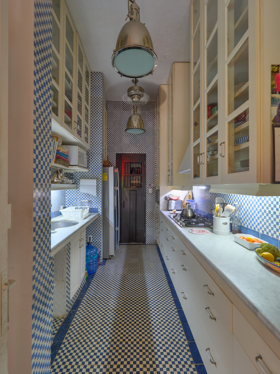 Narrow blue and white tiled galley kitchen