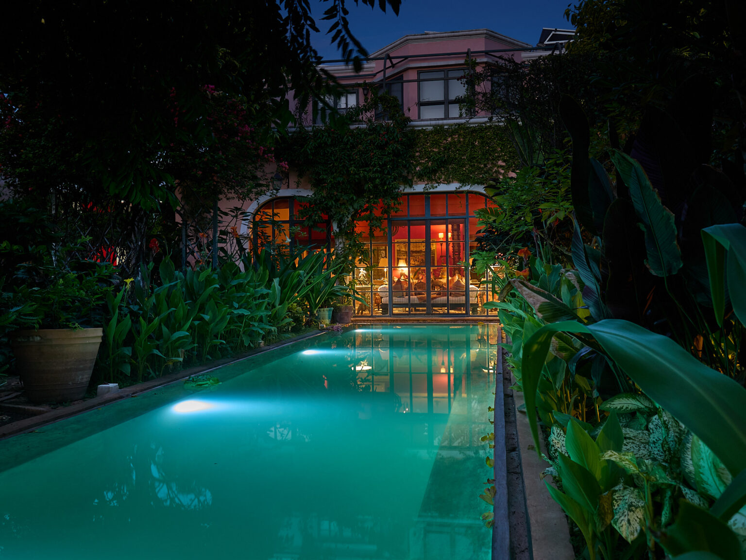 Evening tropical backyard pool in front of house