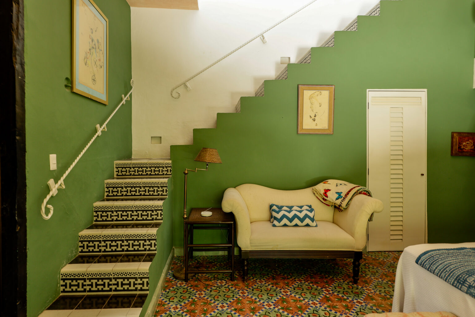 Green-walled room with tiled staircase and loveseat