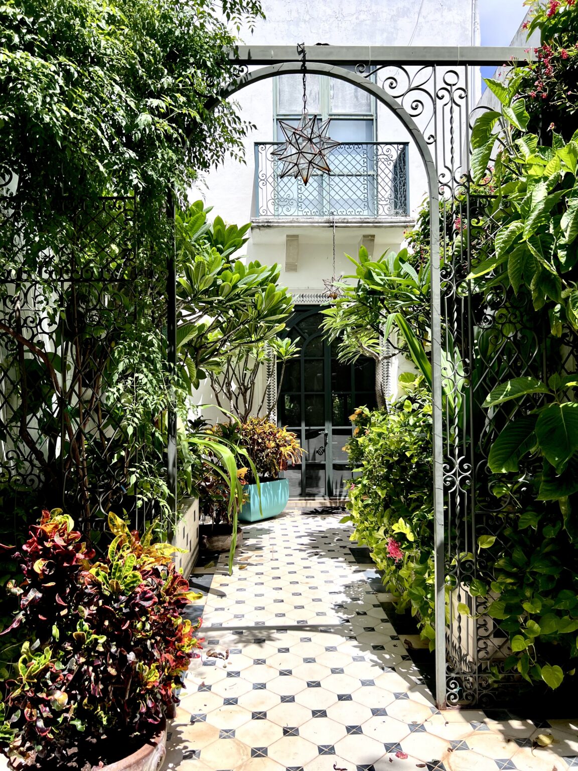 Sunlit tiled courtyard with wrought iron arch