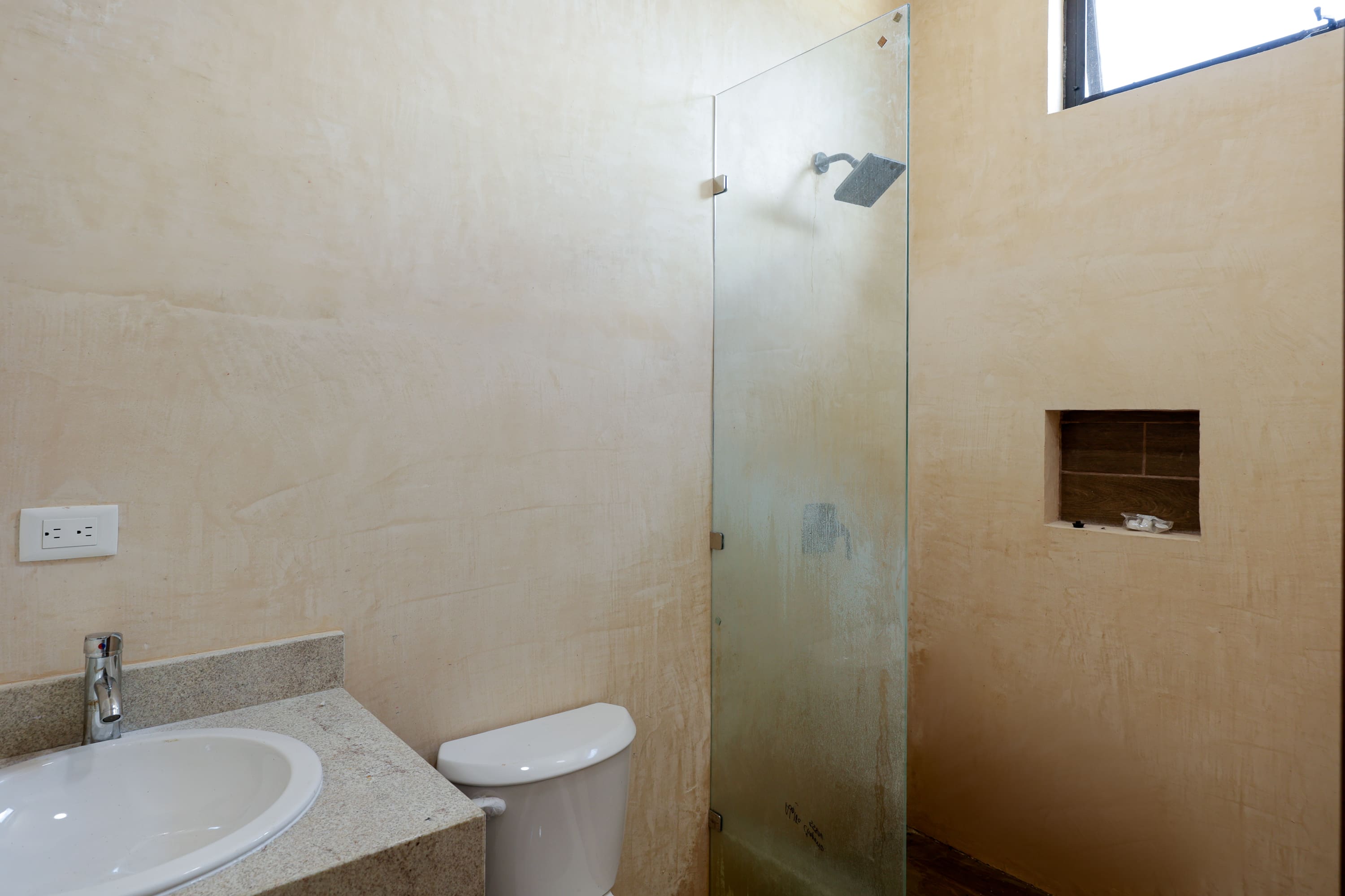 Minimal beige bathroom with glass shower enclosure