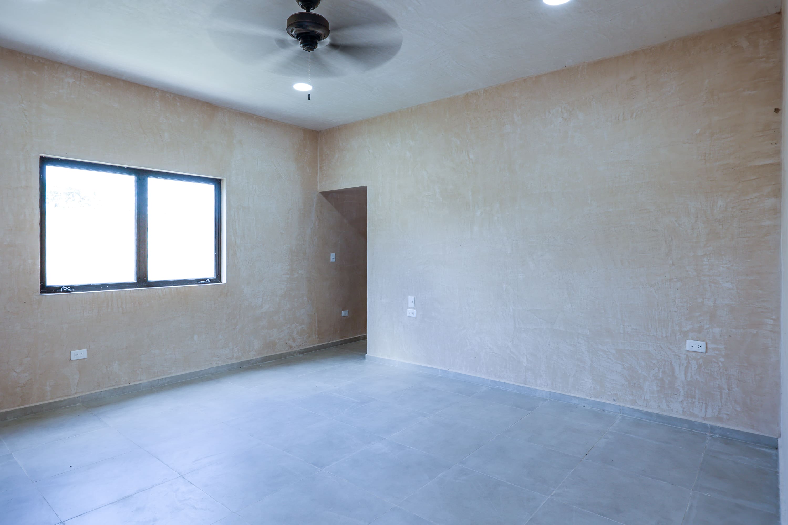 Empty newly plastered room with ceiling fan