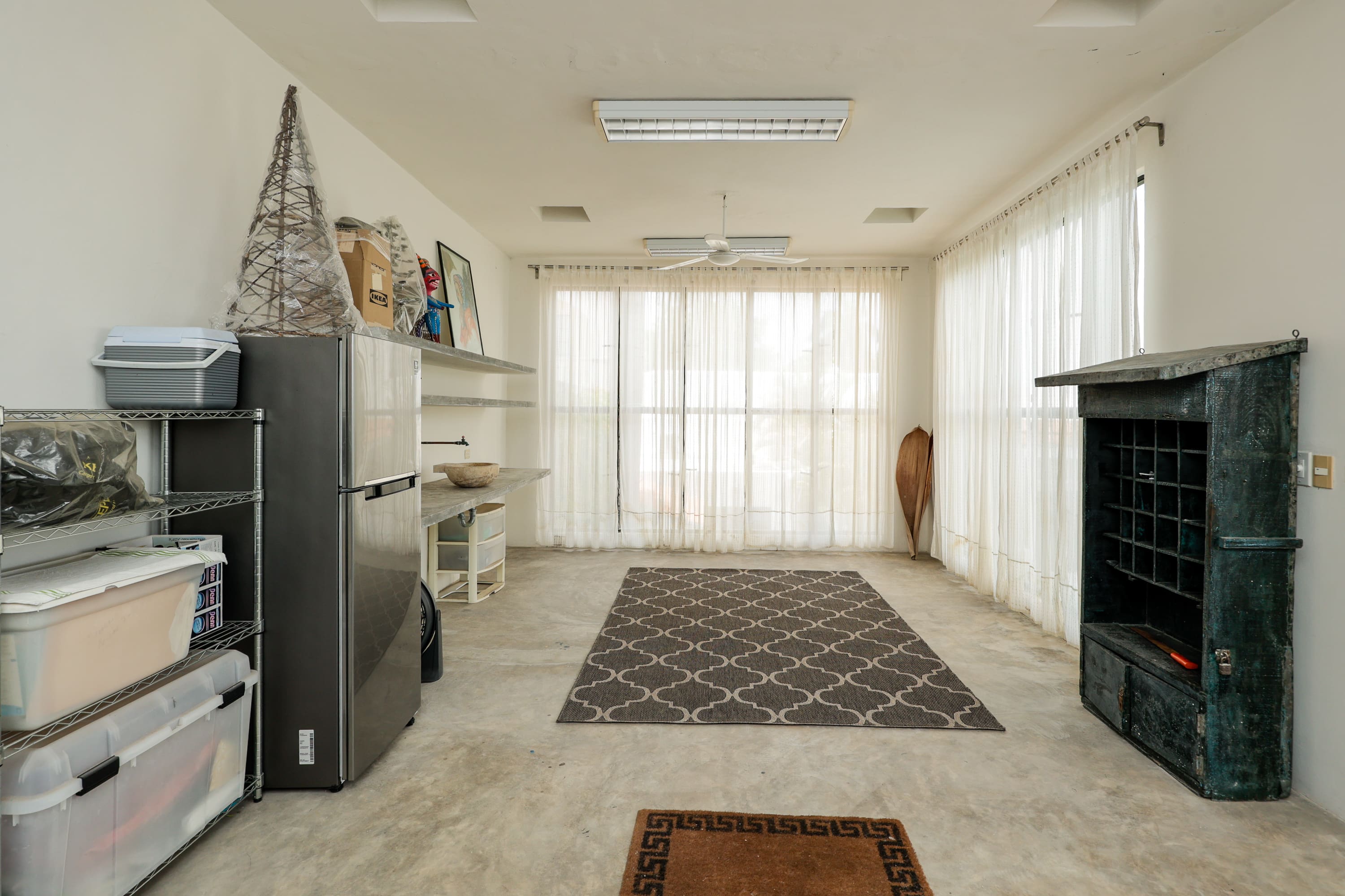 Bright sunroom with rug, refrigerator, storage shelves