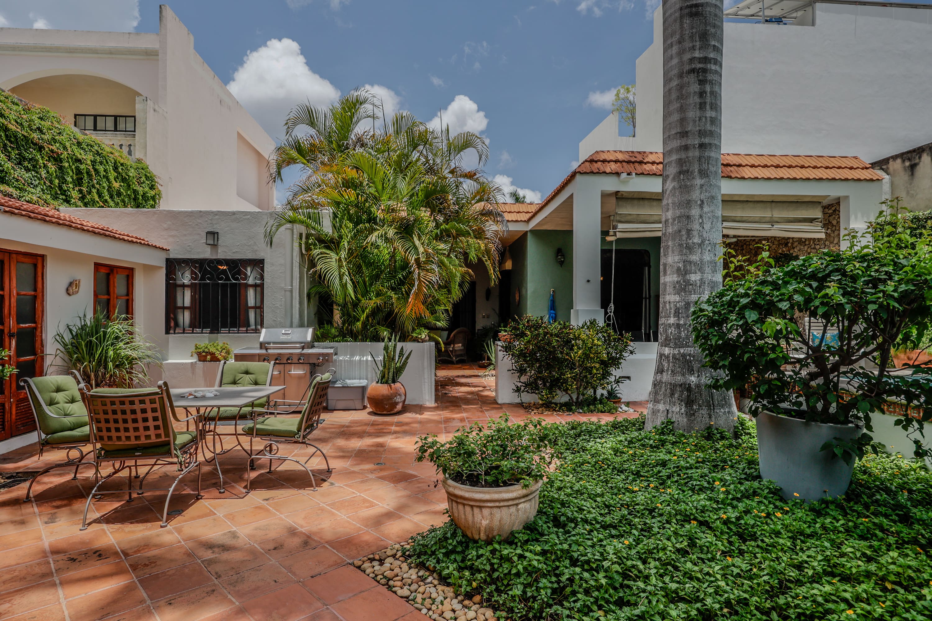 Sunlit tiled courtyard with patio furniture and plants