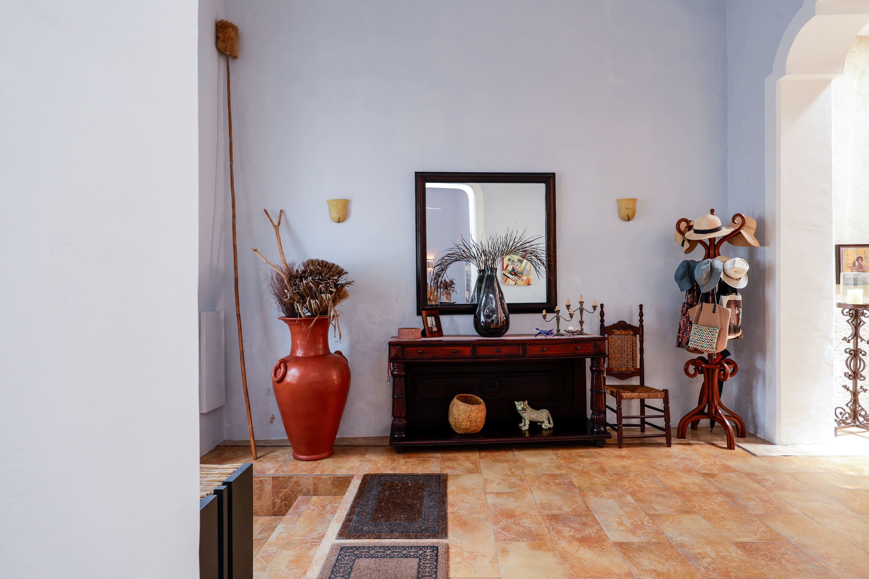 Entryway console with mirror, red vase, hats