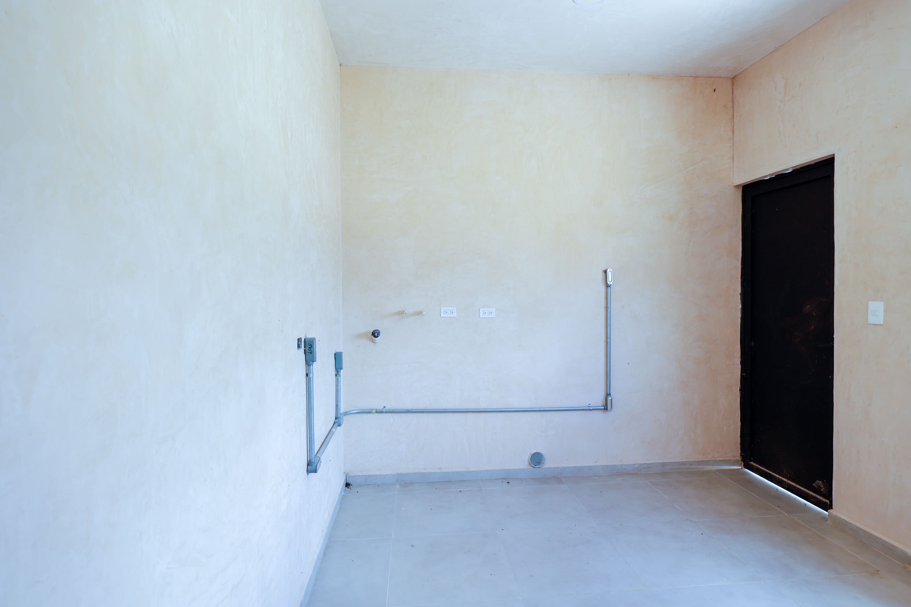 Empty utility room with exposed electrical conduit