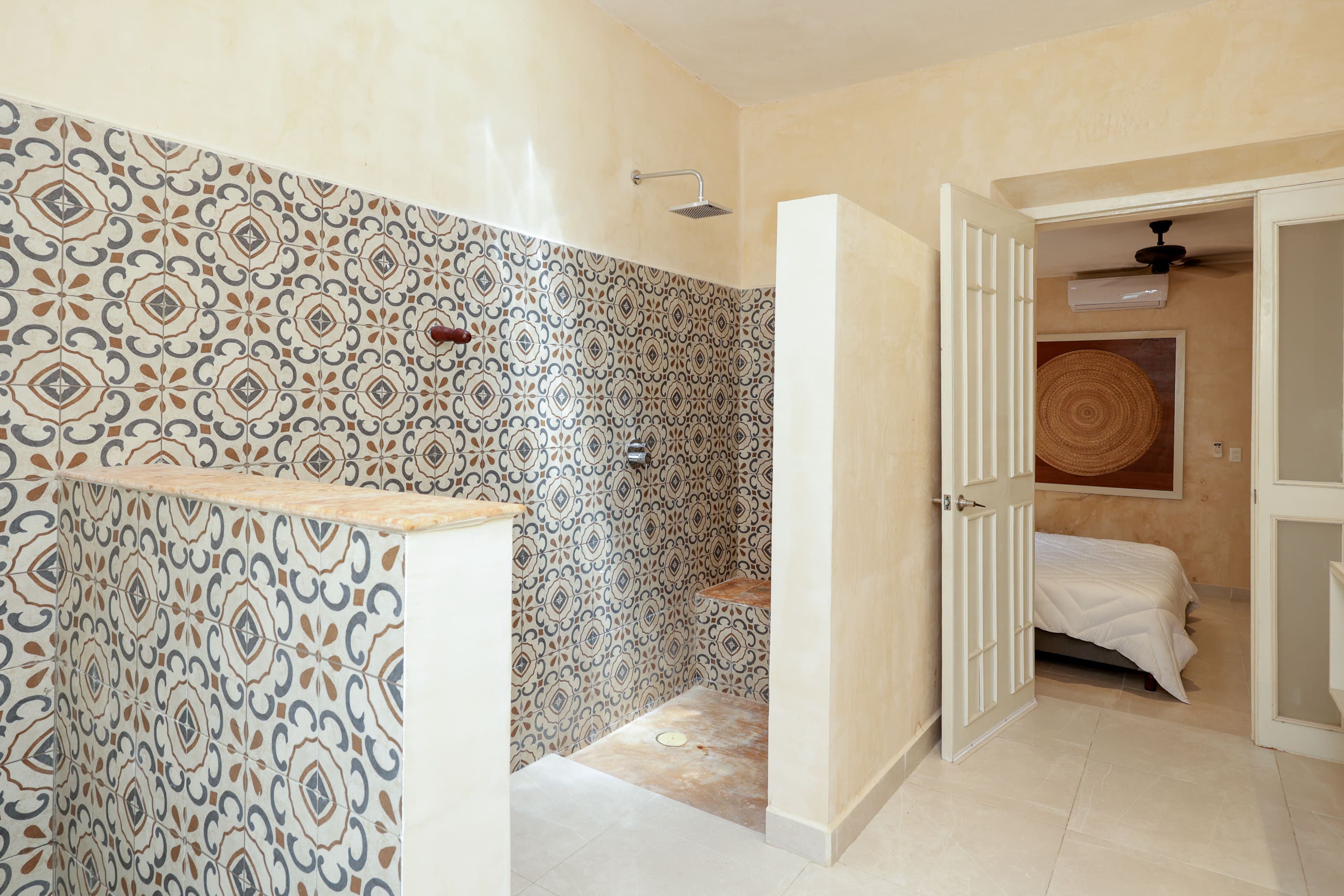 Bathroom with patterned tile shower and bedroom