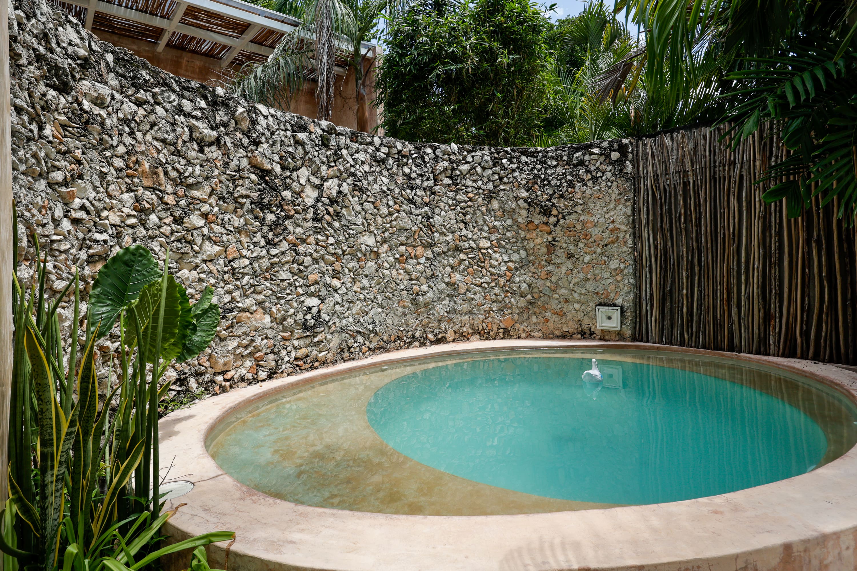 Round turquoise plunge pool enclosed by stone wall