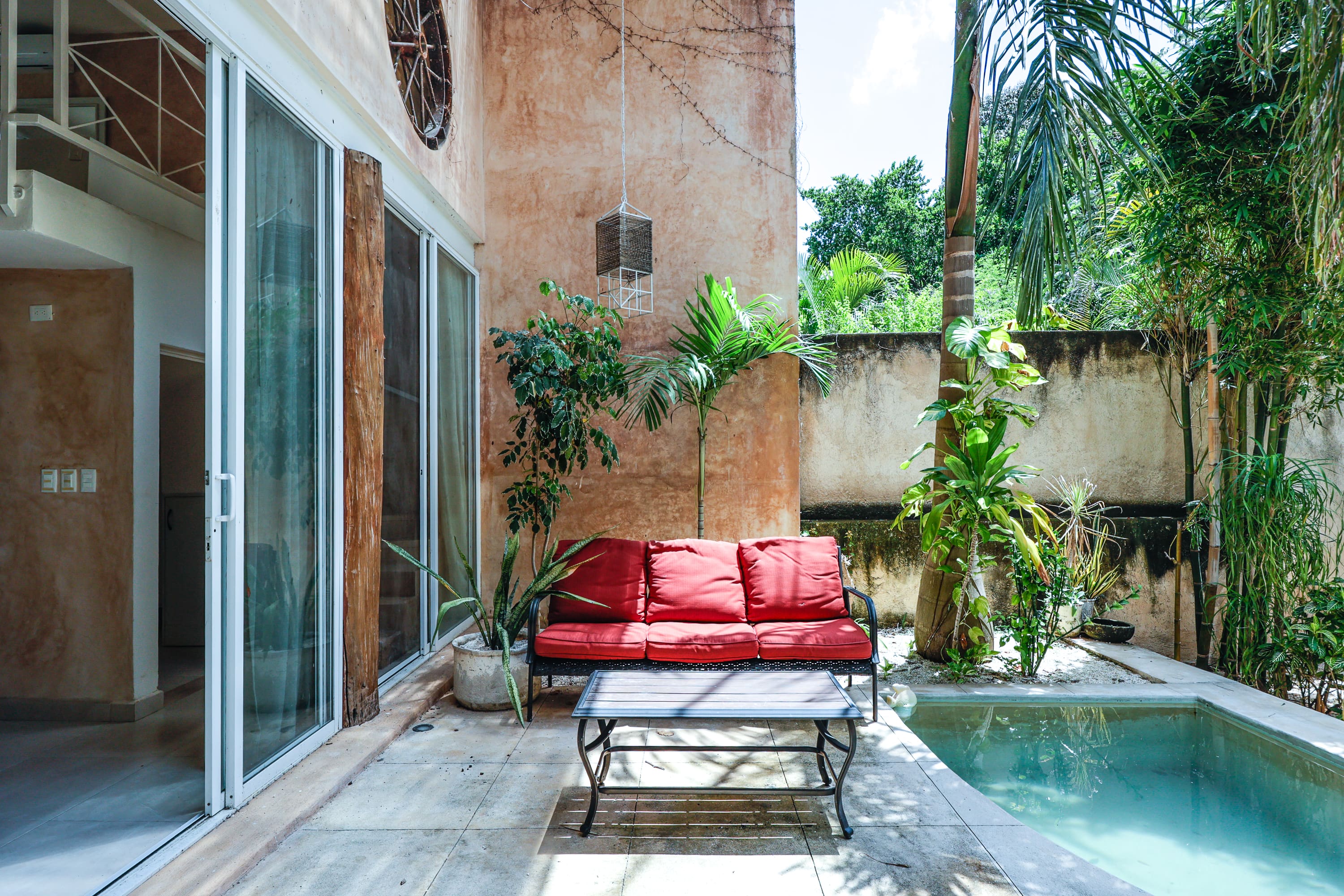 Red outdoor sofa by pool with plants