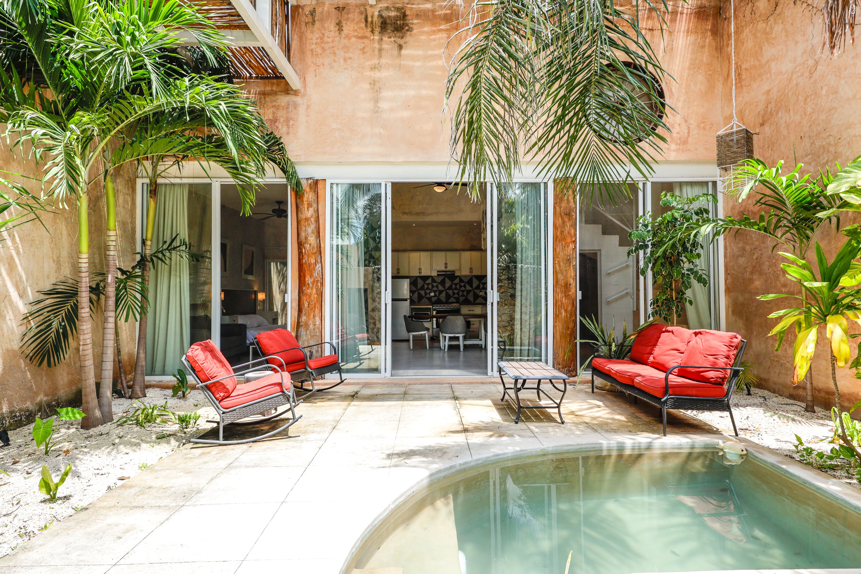 Tropical courtyard with pool and red chairs
